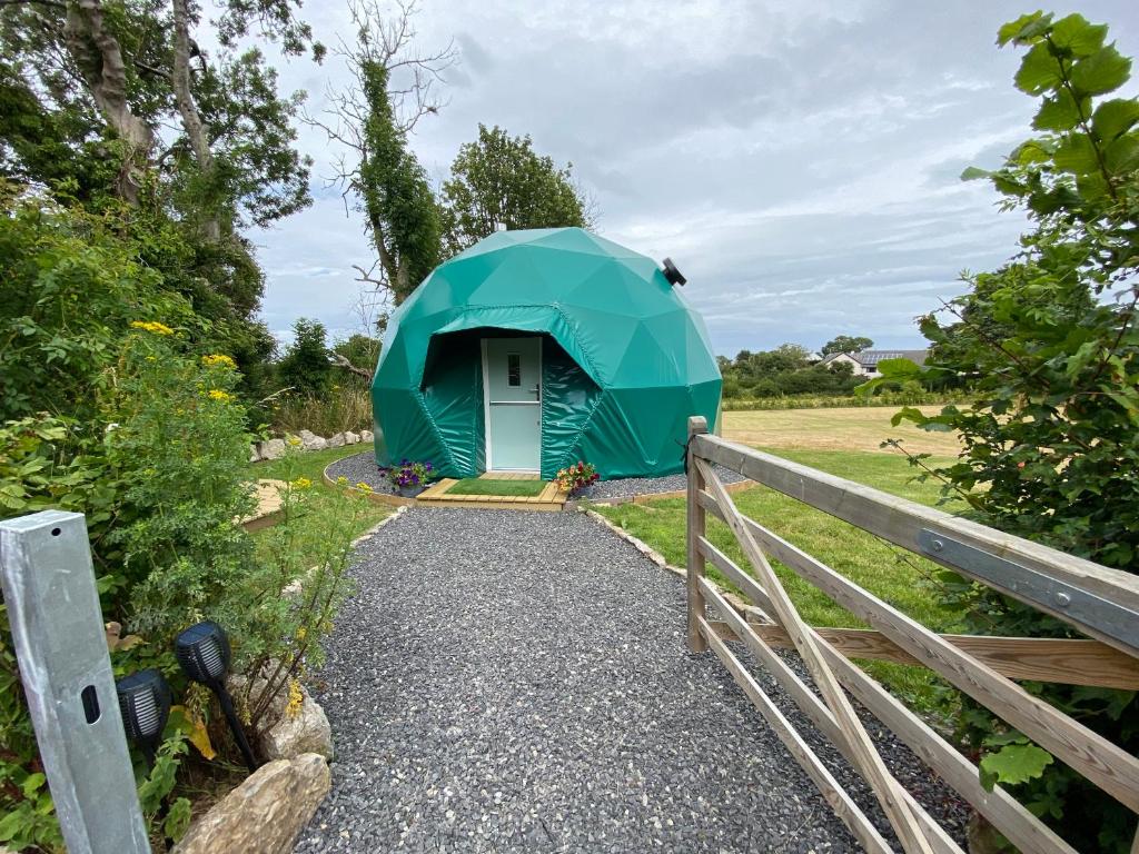 uma tenda verde num campo com uma cerca em Benllech Glamping em Benllech