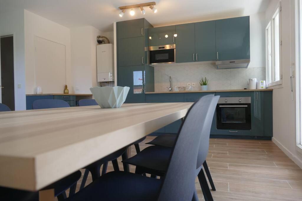 a kitchen with blue cabinets and a table with chairs at Disneyland Paris, appartement 70m², parking privé in Serris