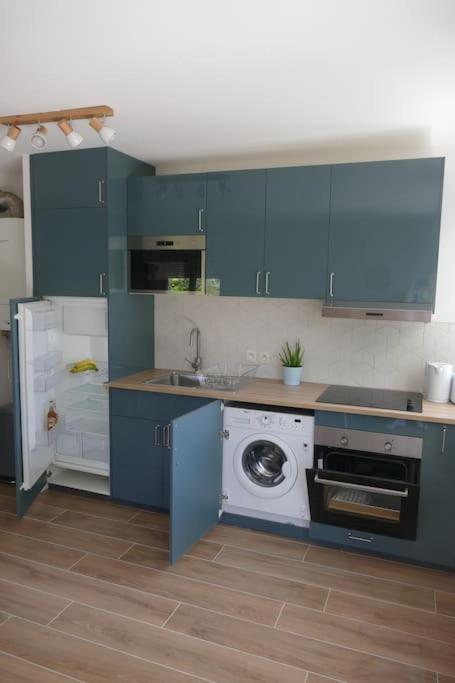 a kitchen with blue cabinets and a washing machine at Disneyland Paris, appartement 70m², parking privé in Serris
