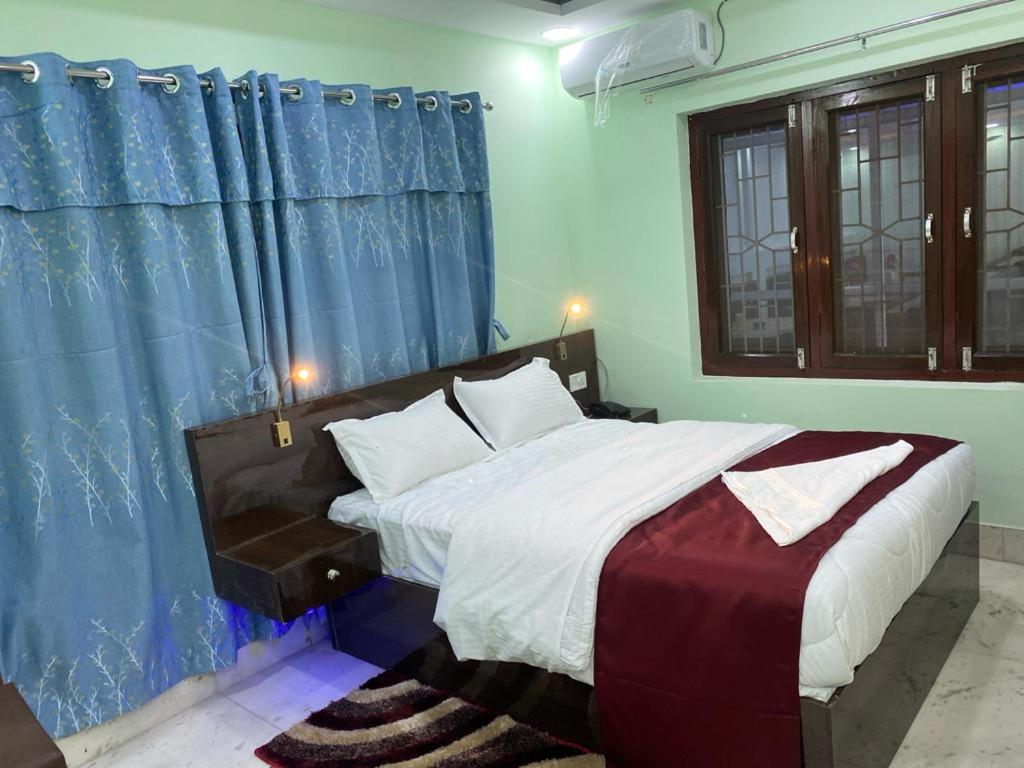 Schlafzimmer mit einem großen Bett und blauen Vorhängen in der Unterkunft Royalwood City Inn in Birātnagar