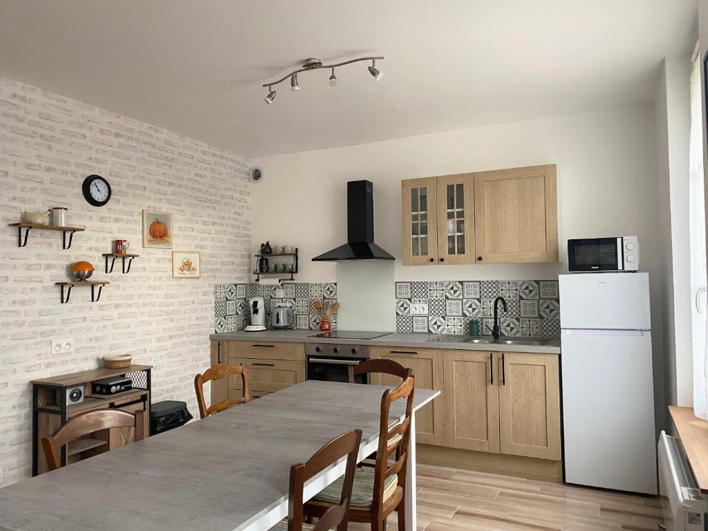 a kitchen with a table and a white refrigerator at Le Clos Aime in Contres