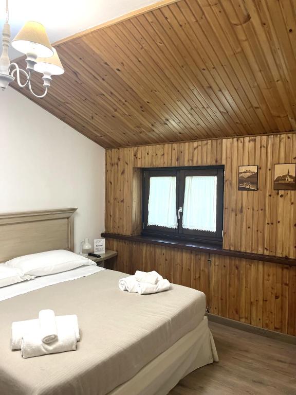 2 łóżka w sypialni z drewnianymi ścianami i oknem w obiekcie HOTEL CAMPO STELLA w mieście Leonessa