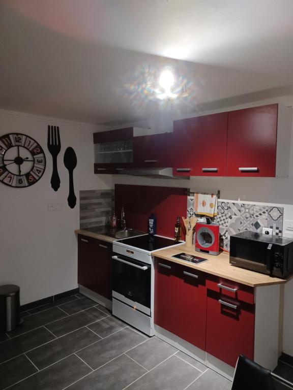 cocina con armarios rojos y fogones en Les Charmes-Balnéothérapie-Vidéoprojecteur-Netflix, en Baume-les-Dames