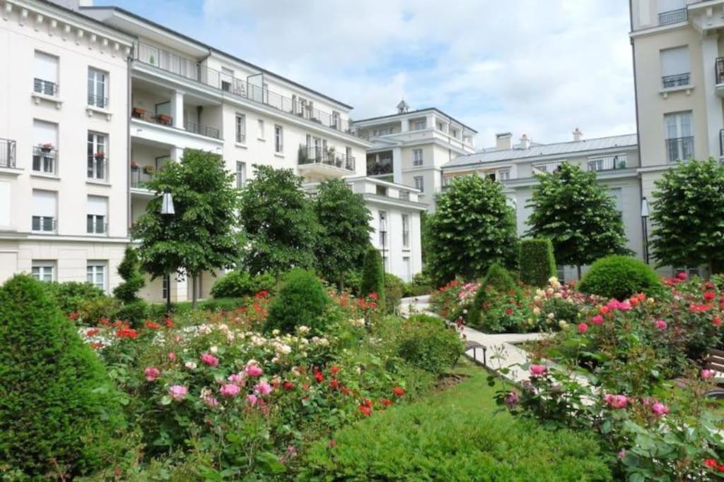 un jardín frente a un edificio con flores en Le Royal Condo, 13 P, WIFI & Parking à Disneyland, en Chessy