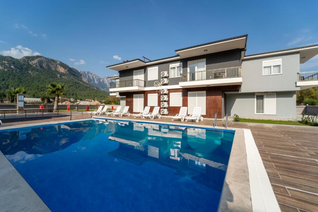 a swimming pool in front of a house with mountains at Göynük Panorama Luxury Otel in Kemer