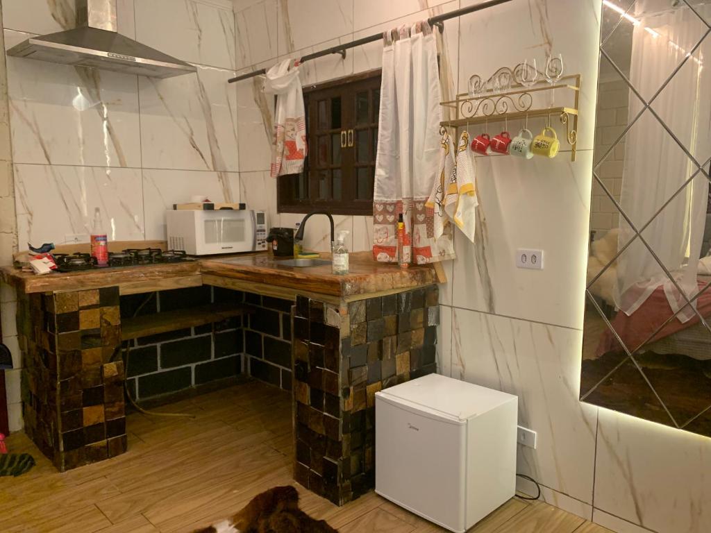 eine kleine Küche mit einer Theke und einem Kühlschrank in der Unterkunft Chalé Romântico Campina Grande do sul in Campina Grande do Sul