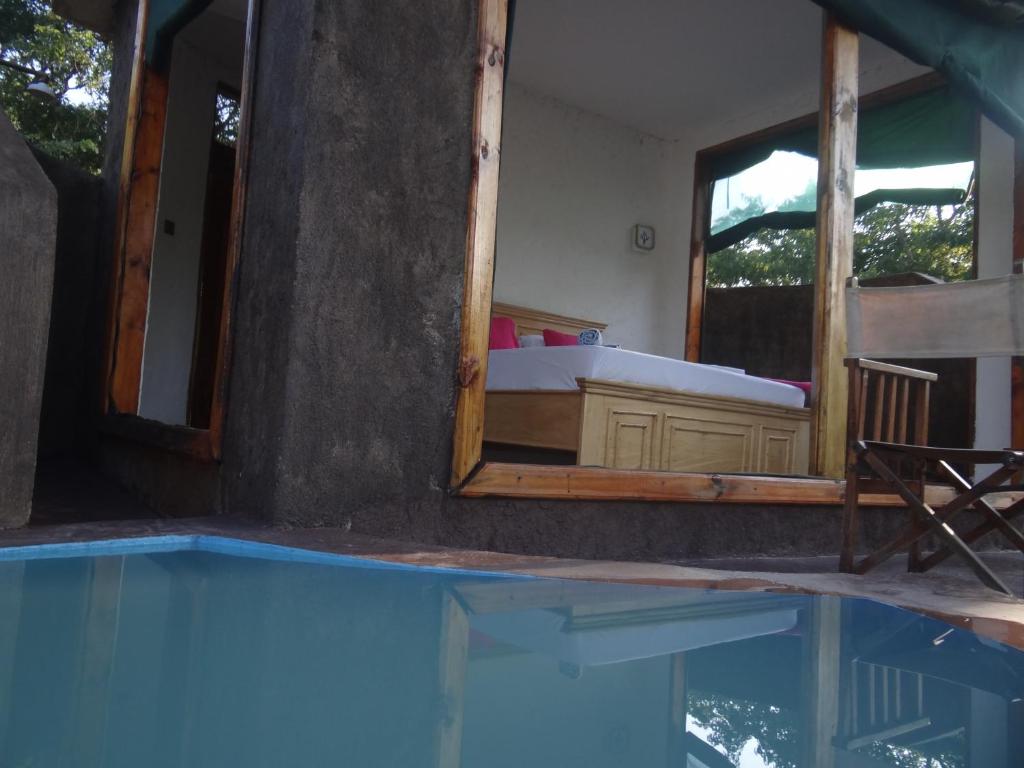 a bedroom with a tub and a mirror and a swimming pool at Doublegsafaris and camp mikumi in Mikumi