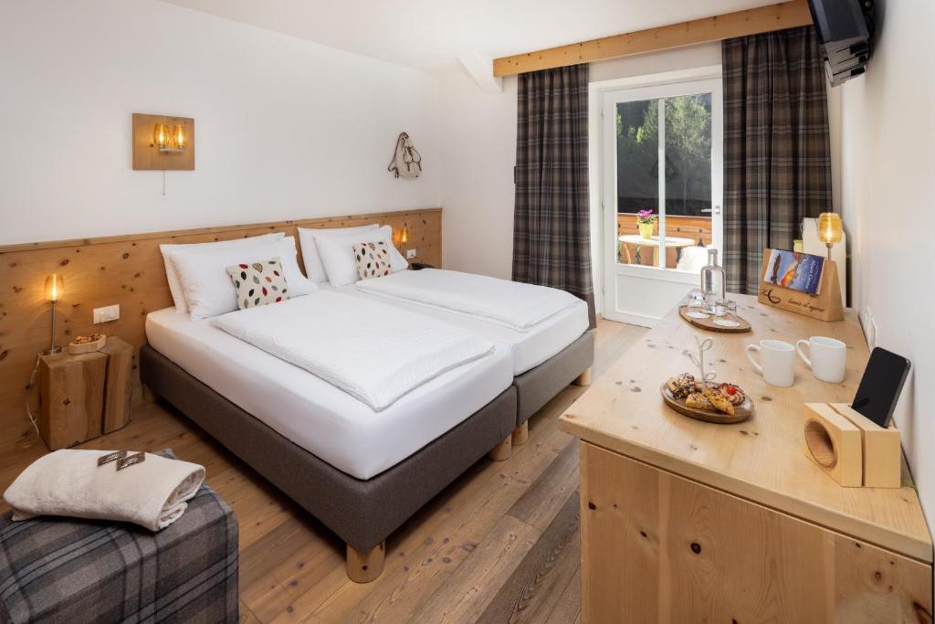 una camera d'albergo con letto, scrivania e letto Sidx Sidx. di Small & Lovely Hotel Zaluna a Predazzo