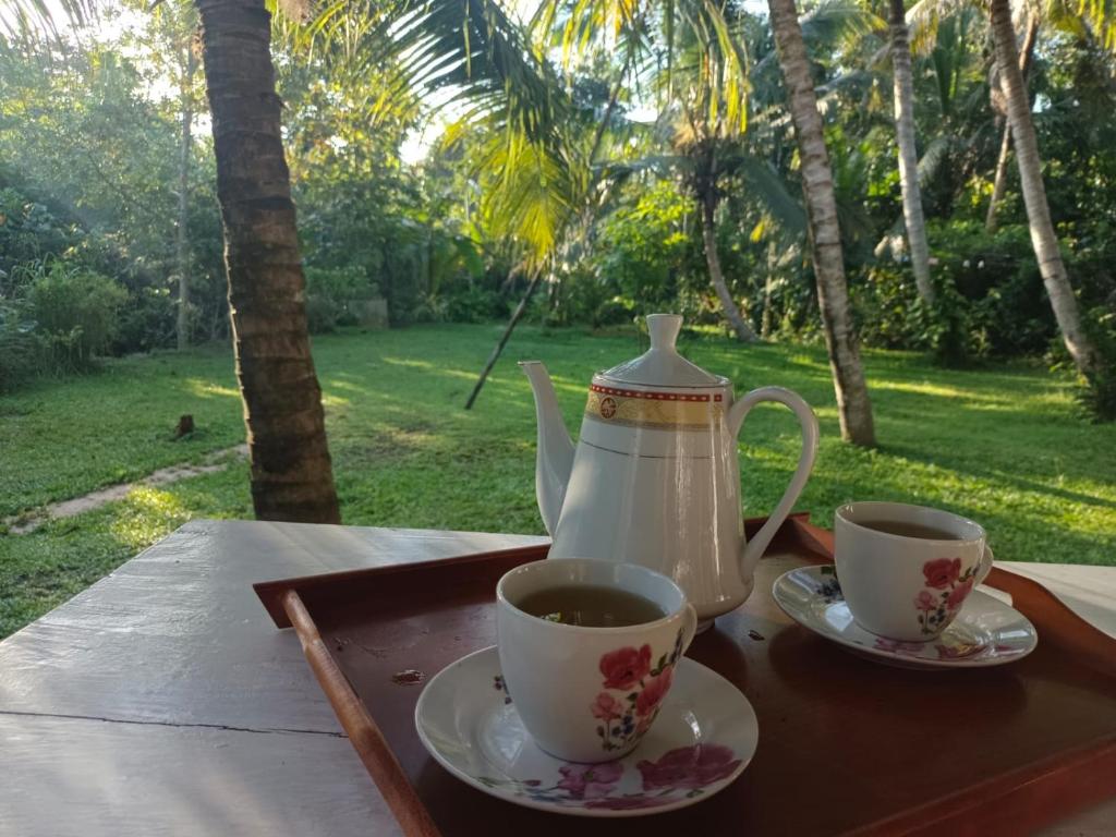 a tea pot and two cups on a table at Sonya Garden View in Weligama