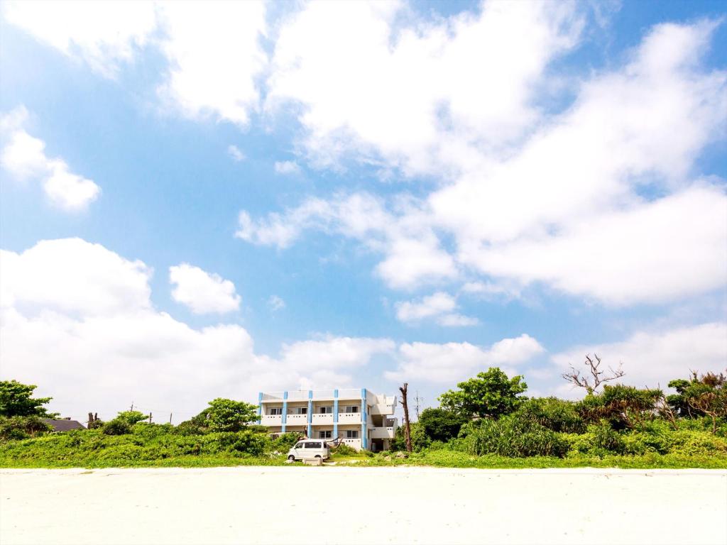 a building on the beach with a cloudy sky at Uminchuno Yado in Nago