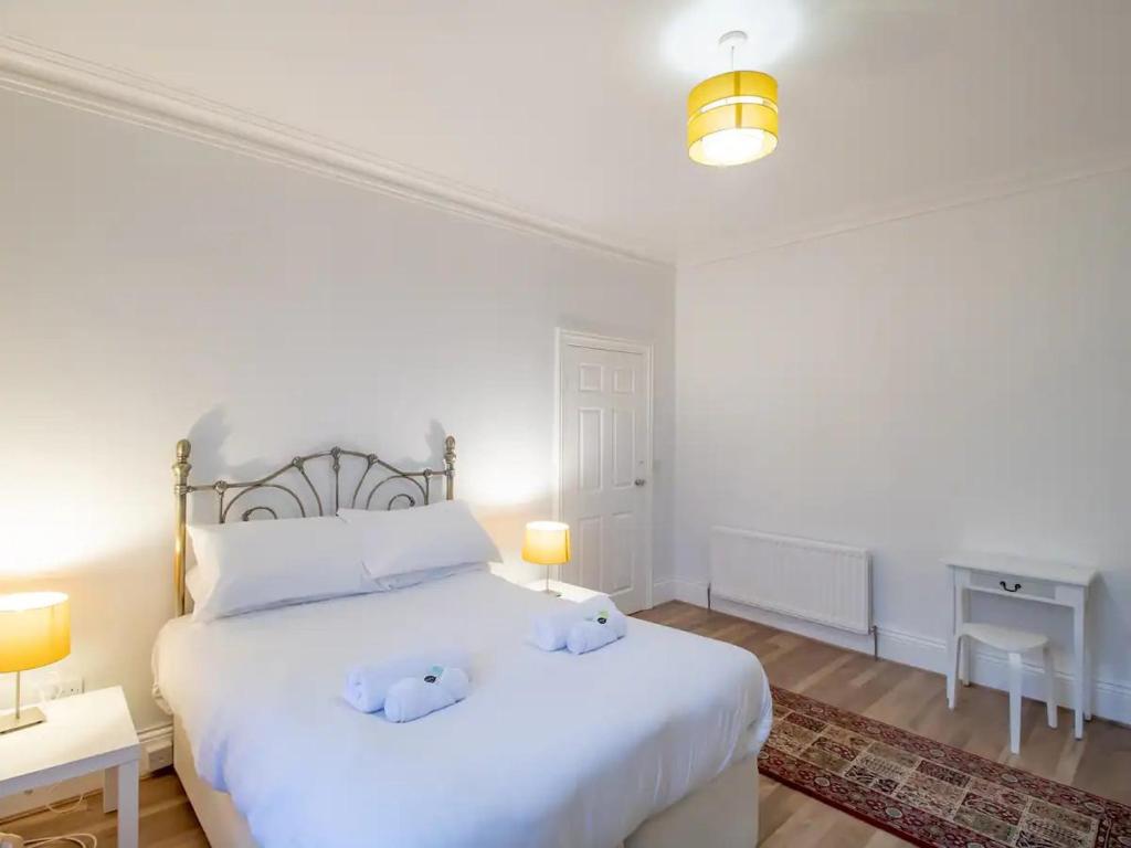 a bedroom with a white bed with two stuffed animals on it at Pass the Keys Cosy Flat in Newcastle Upon Tyne in Elswick