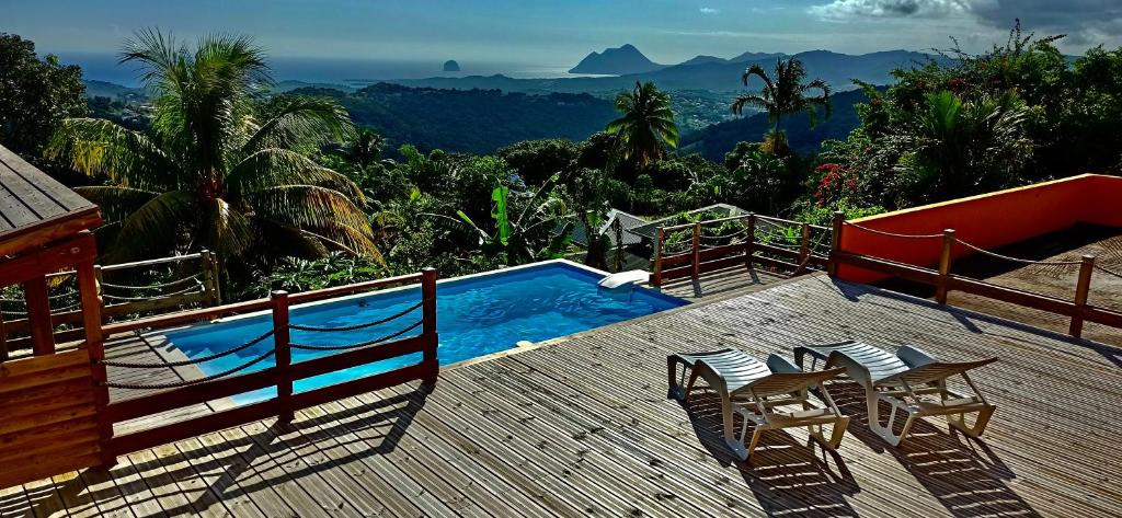 a deck with a pool and chairs and a view of the mountains at Villa CosaRoé Martinique Piscine et superbe vue mer in Rivière-Salée