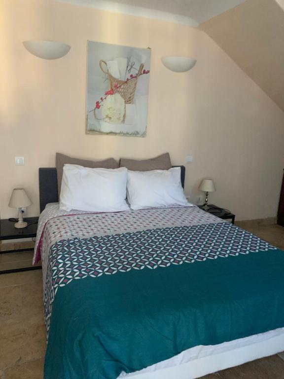Schlafzimmer mit einem Bett mit einer grünen und weißen Bettdecke in der Unterkunft Hotel La Fuste in Valensole