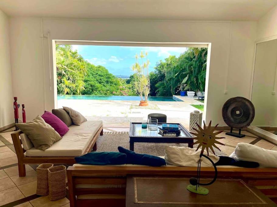sala de estar con sofá y vistas al océano en Maison La Samana, en Baie-Mahault