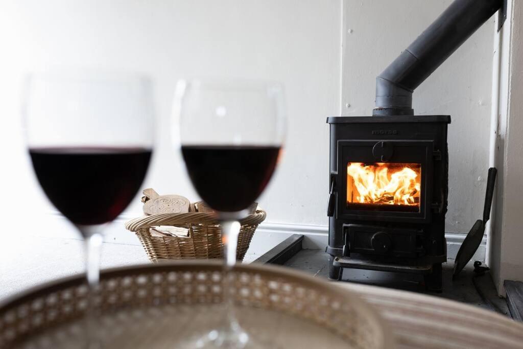 two glasses of red wine in front of a fireplace at Peaceful and cosy retreat near Llandeilo in Llanfynydd