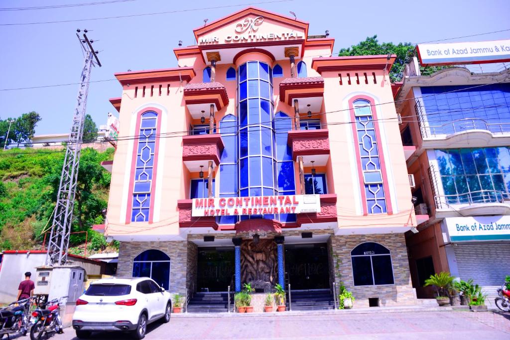 a building with a car parked in front of it at Mir Continental Hotel & Restaurant in Muzaffarabad