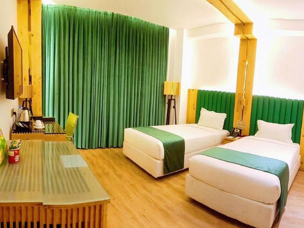 two beds in a hotel room with green curtains at Grace Cox Smart Hotel in Cox's Bazar
