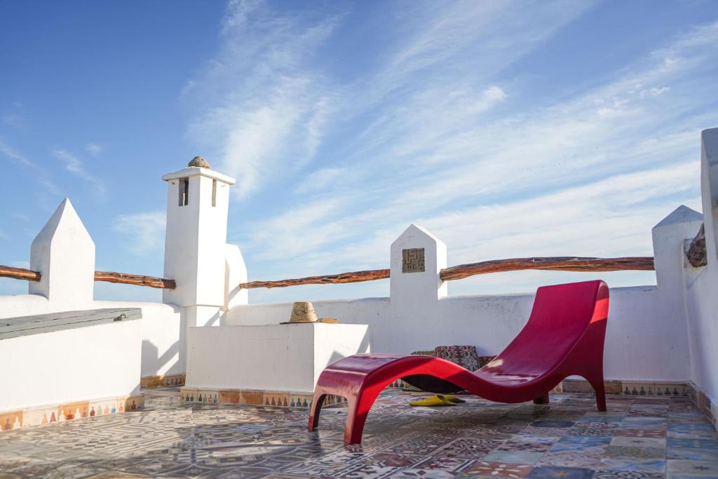 a red chair sitting on the side of a white building at Dar 91 Essaouira in Essaouira