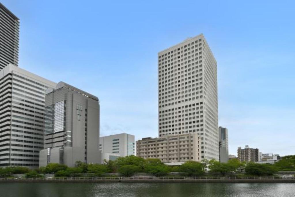 a city skyline with tall buildings and a river at Hotel NCB in Osaka