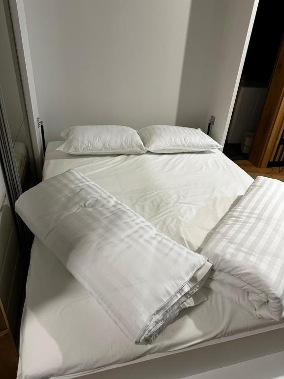 a bed with white sheets and pillows on it at Apartment Aurora in Bjelašnica