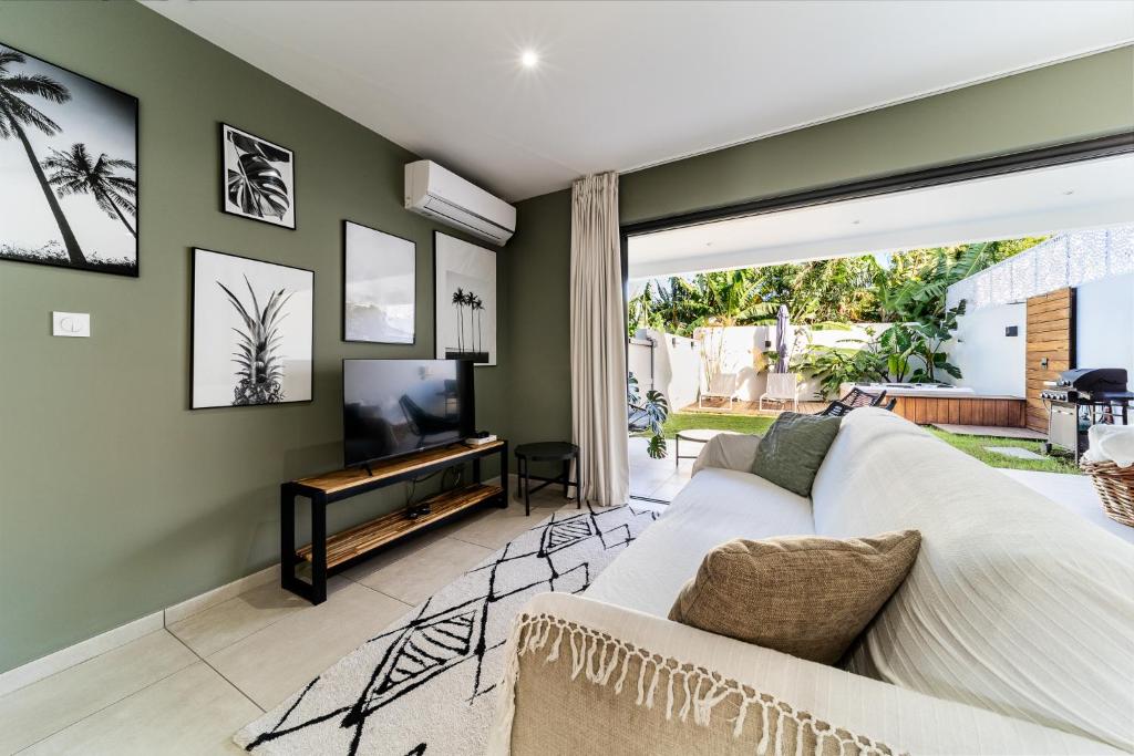 a living room with a white couch and a tv at Magnifique villa avec jacuzzi Proximité mer in Saint-Joseph