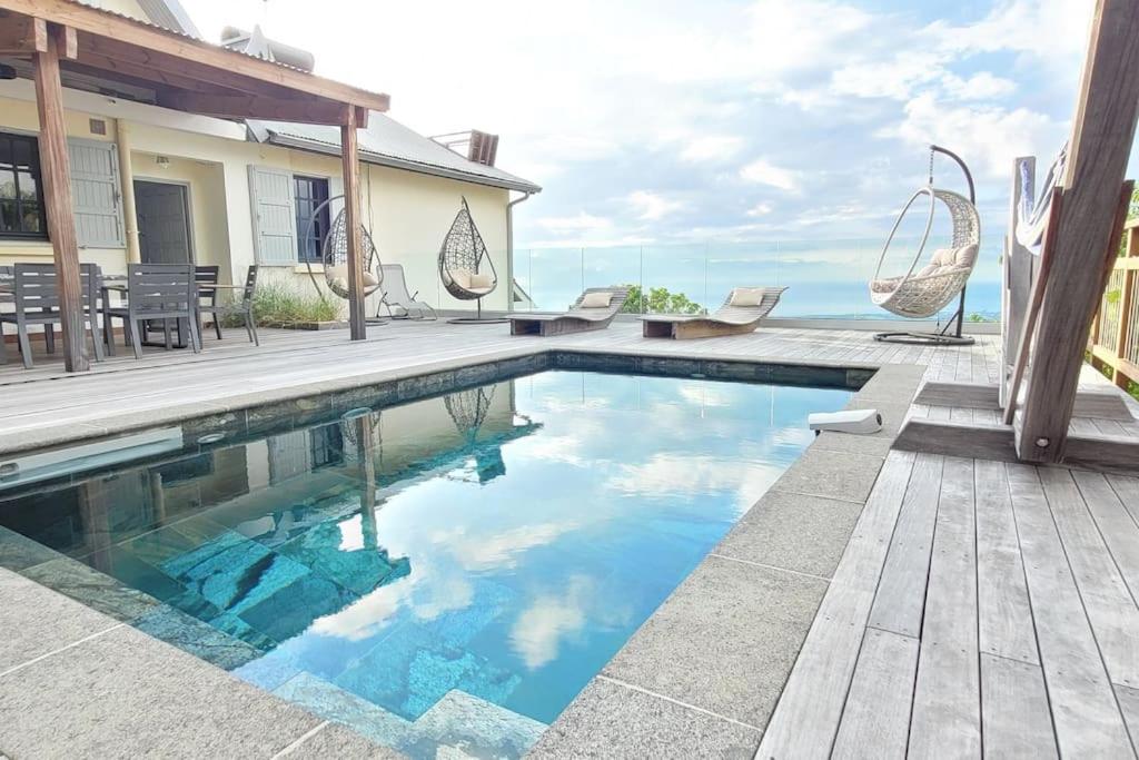 a swimming pool with a deck and a house at Au Bel Endormi in Saint-Paul