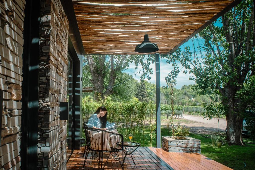 a woman sitting on the porch of a house at Lodwine Lodge Apartments in Ciudad Lujan de Cuyo