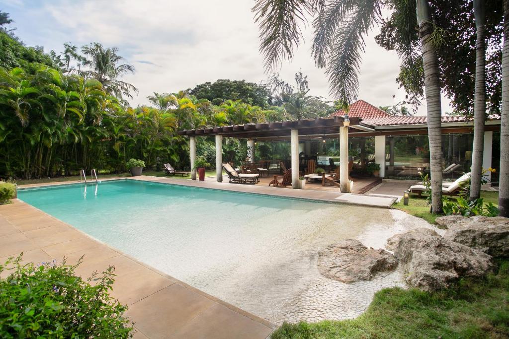 a swimming pool with a gazebo next to a house at Fontana di Rosa, African Style Villa Casa de Campo in La Romana