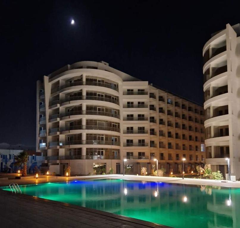 a large building with a swimming pool at night at Scandic beach resort in Hurghada