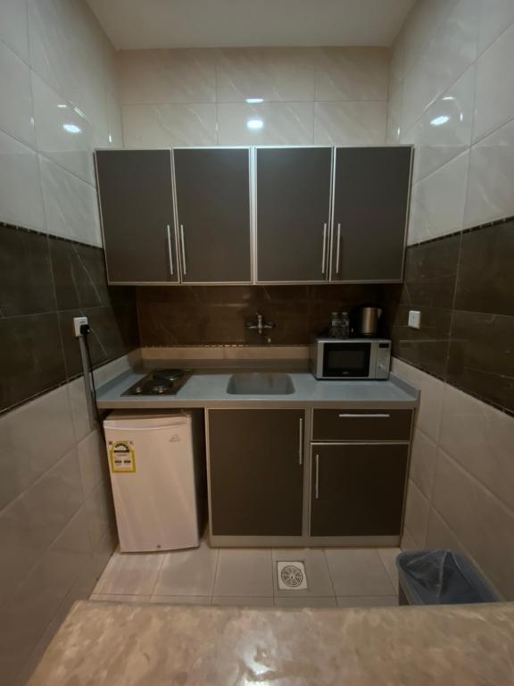 a small kitchen with brown cabinets and a microwave at فندق بيوتات المروة biutat almarwa in Jeddah