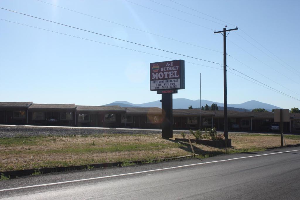 een bord aan de kant van een weg naast een trein bij A-1 Budget Motel in Klamath Falls