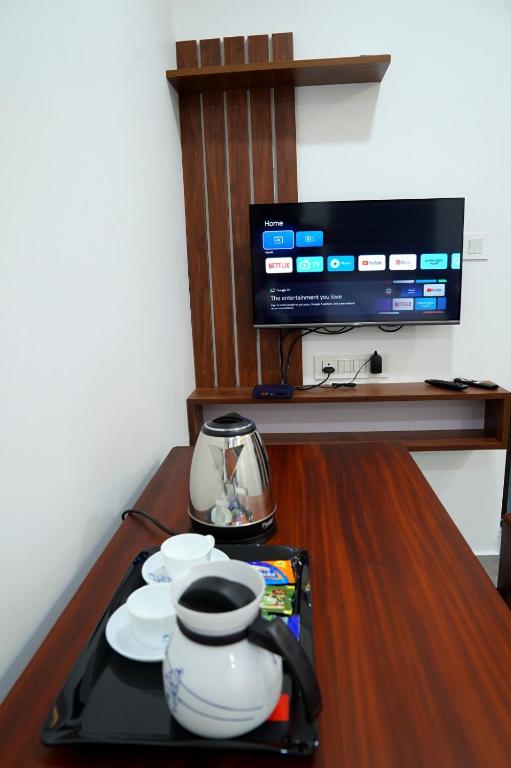 un tavolo con un vassoio con piatti e una TV di UNIVERSAL RESIDENCY a Perumpāvūr
