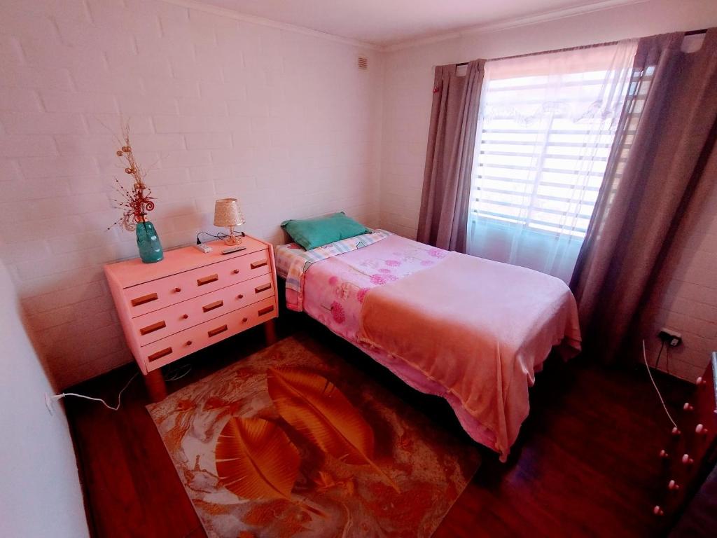 ein Schlafzimmer mit einem Bett, einer Kommode und einem Fenster in der Unterkunft Habitación hogareña in Curicó
