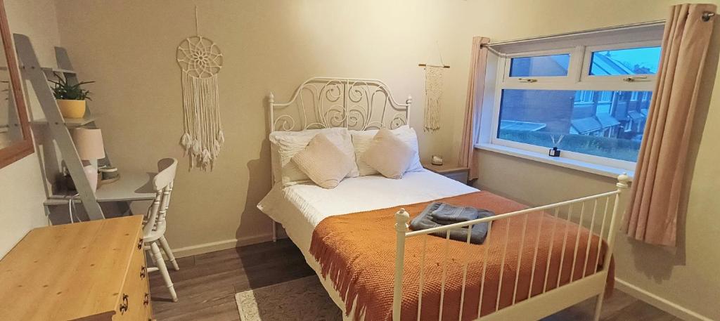 a bedroom with a bed and a desk and a window at Homestay close to the hospital and Alton Towers with resident dog and cat in Stoke on Trent