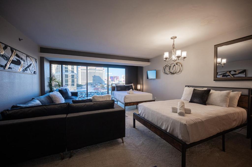 a bedroom with a bed and a couch and a window at Iconic Vegas Views - 6 comfy Beds, NO RESORT FEES, Center Strip! in Las Vegas