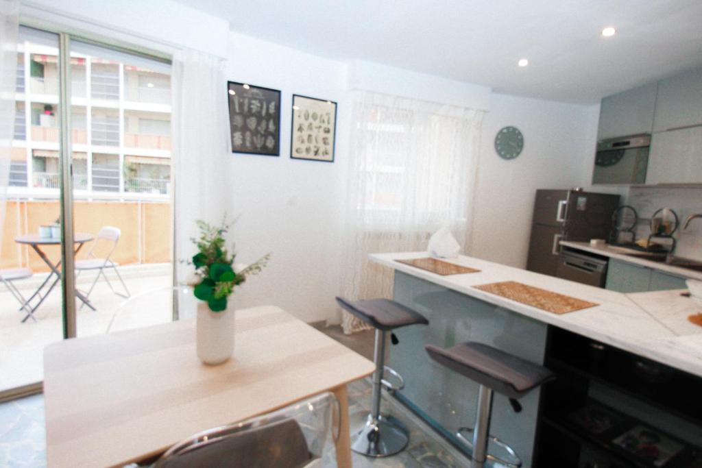 une cuisine avec une table avec un vase de fleurs dessus dans l'établissement Les Bouleaux YourHostHelper, à Cagnes-sur-Mer