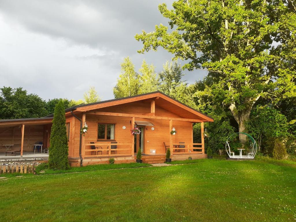 una cabaña de madera con un césped verde delante de ella en Forest Edge Cottage en Riga