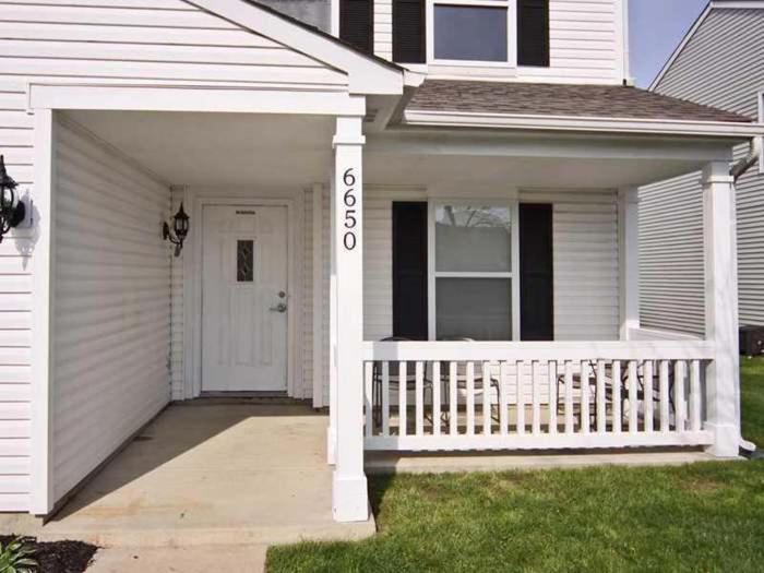 a white house with a porch and a white door at Carlena Massage Center in Indianapolis
