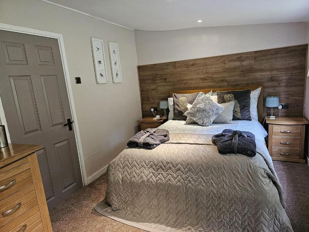 a bedroom with a large bed with a wooden headboard at Rowan Tree Lodge with hot tub in Hope Bagot