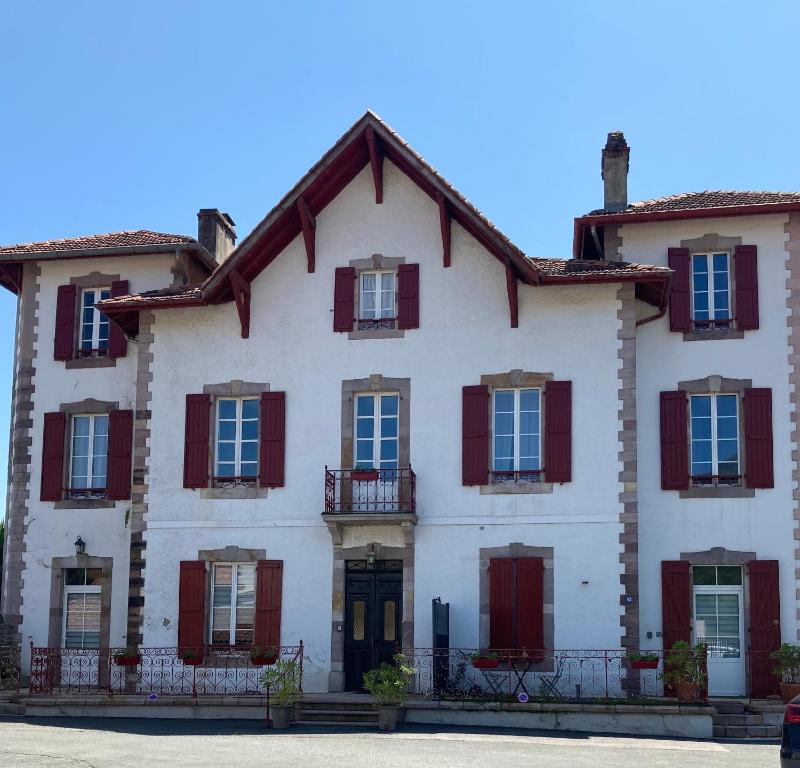 una gran casa blanca con persianas rojas en Maison Graciateguy en Saint-Étienne-de-Baïgorry