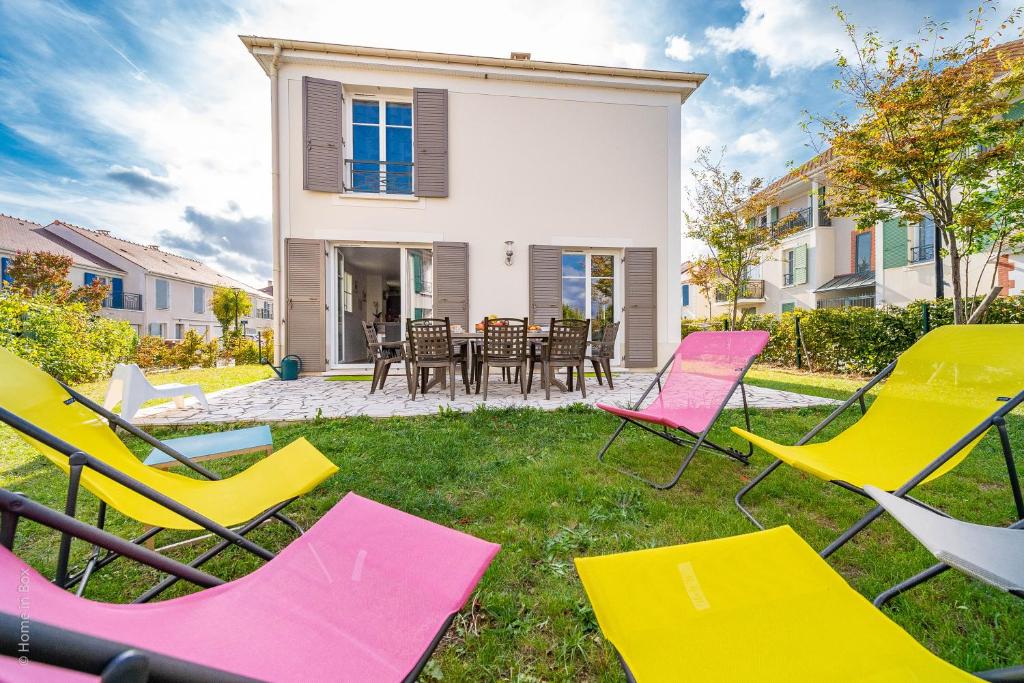 eine Gruppe von Stühlen und Tischen vor einem Haus in der Unterkunft Gîte La Villa Omagny Paris Marne-la-Vallée in Magny-le-Hongre