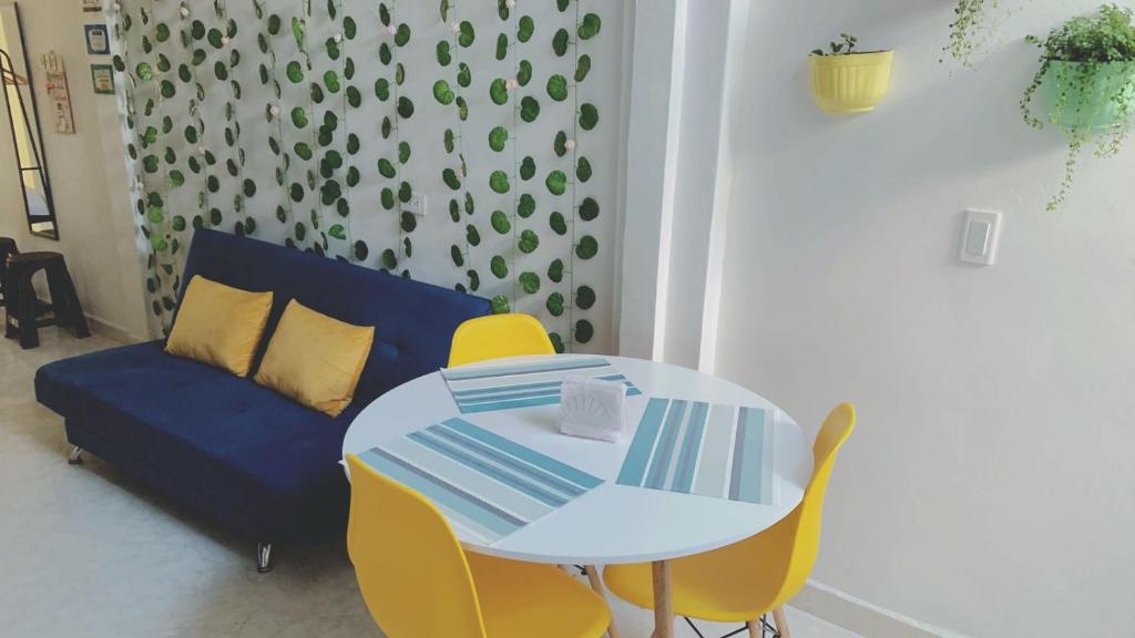 a white table with yellow chairs and a blue couch at habitacion privada en Jardin cerca al parque in Jardin