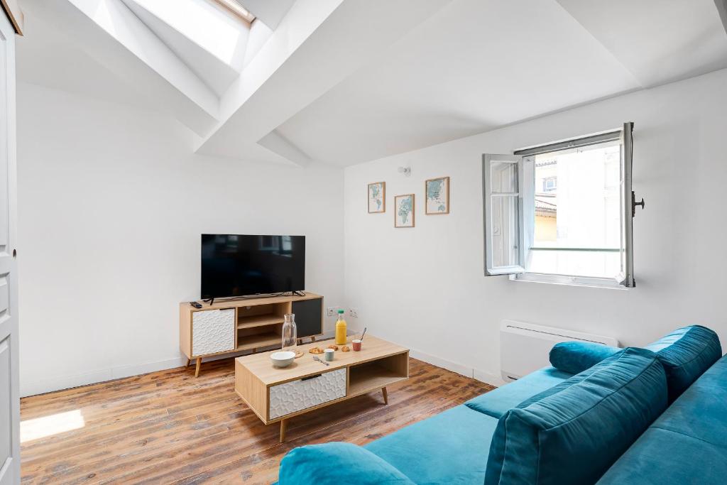 a living room with a blue couch and a tv at Les studios Jean Bringer - Carcassonne centre-ville in Carcassonne