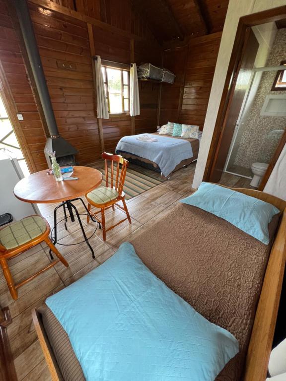 a room with two beds and a table and a tableasteryasteryasteryasteryastery at Chalé na Serra Urubici in Urubici