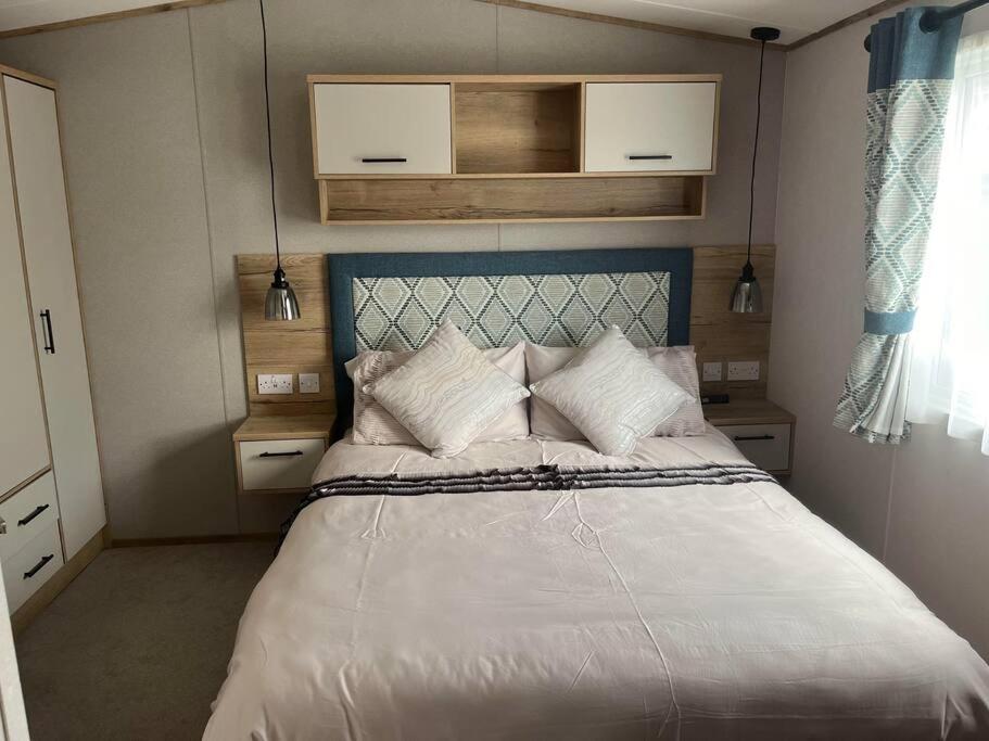 una camera da letto con letto, lenzuola e cuscini bianchi di Coastal caravan with superb view a Bembridge