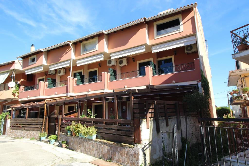 ein orangefarbenes Gebäude mit Balkon auf einer Straße in der Unterkunft Panos Apartments in Benitses