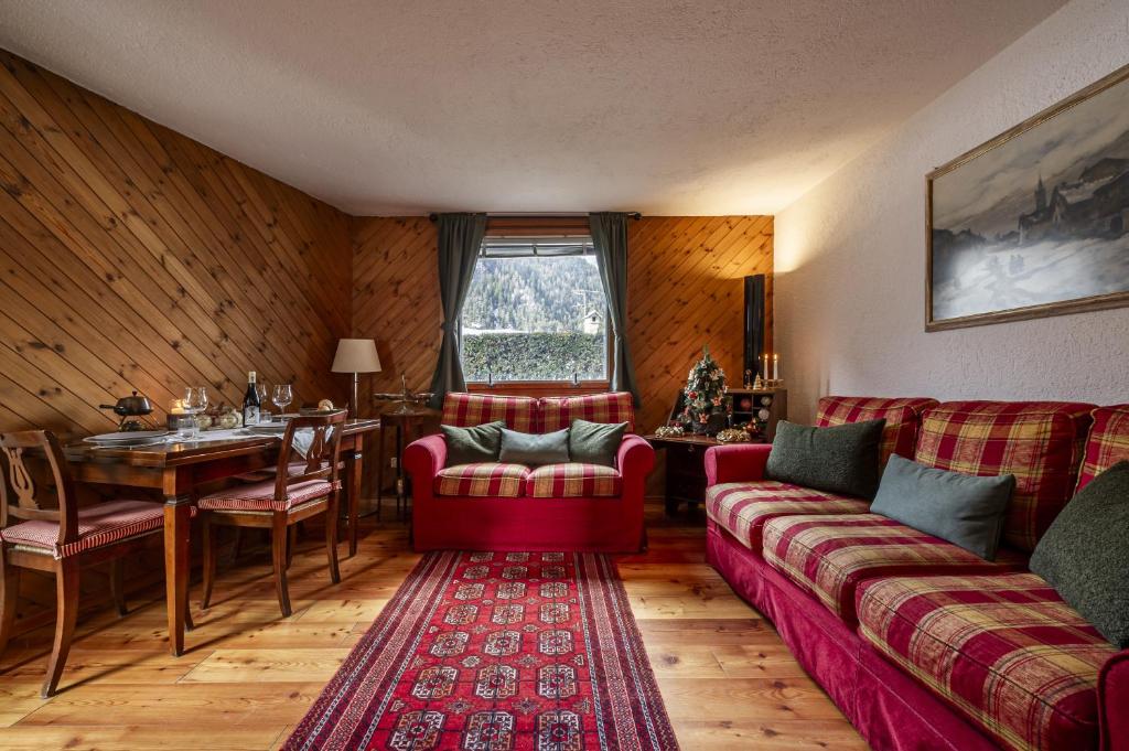 een woonkamer met een rode bank en een tafel bij Maison Simone - wifi parking and mountain view in Courmayeur