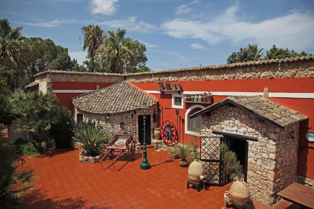 a red building with a brick yard with a patio at Agriturismo Papyrus in Siracusa