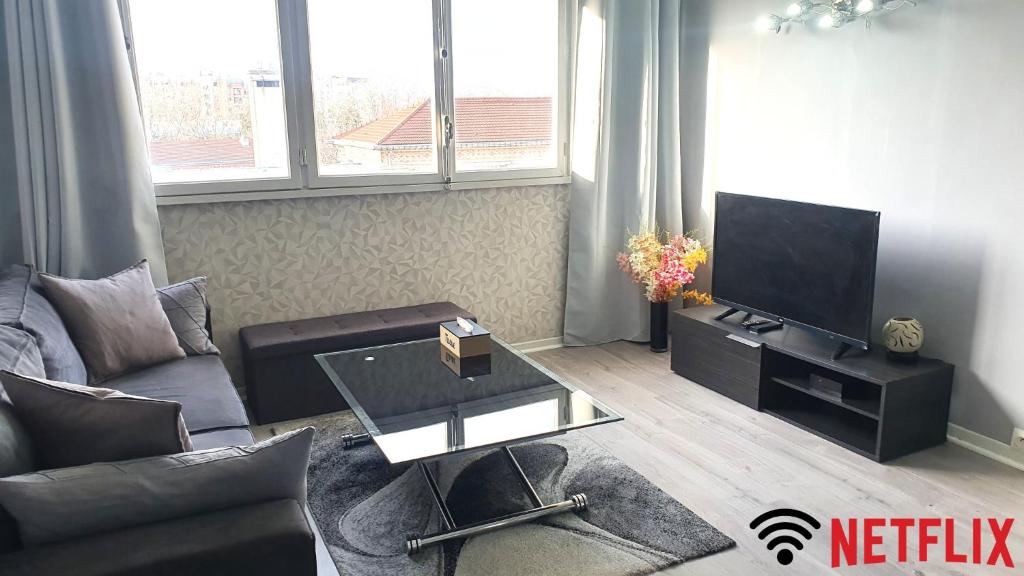 ein Wohnzimmer mit einem Sofa und einem TV in der Unterkunft Charmant et Spacieux Appartement in Le Pré-Saint-Gervais