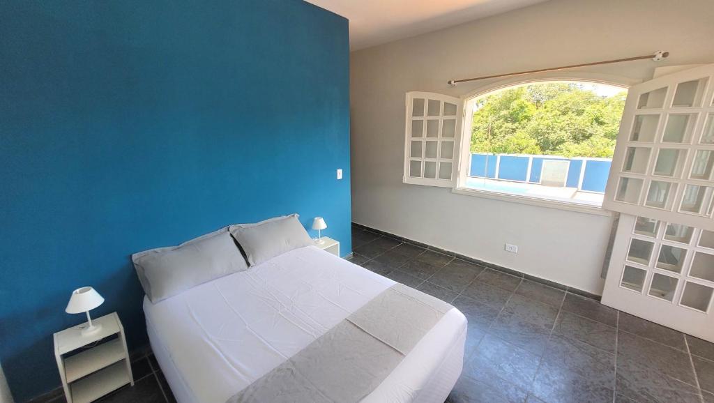 1 dormitorio con cama blanca y pared azul en Pousada Genesis Guaruja, en Guarujá